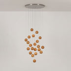 A Clérachic wood pendant on a round ceiling plate, with the spheres in a loose diamond shape on a pale wall.