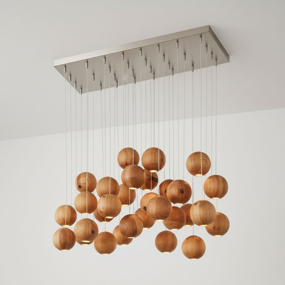 A large Clérachic pendant with many wood spheres under a wide rectangular ceiling plate, in a pale room corner.