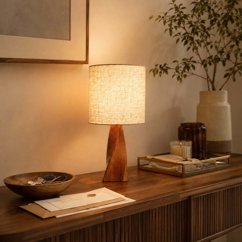 Warm light from this Clérachic table lamp falls on a ribbed wooden console with a wooden bowl, letters, a glass tray and a tall vase.
