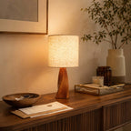 Warm light from this Clérachic table lamp falls on a ribbed wooden console with a wooden bowl, letters, a glass tray and a tall vase.