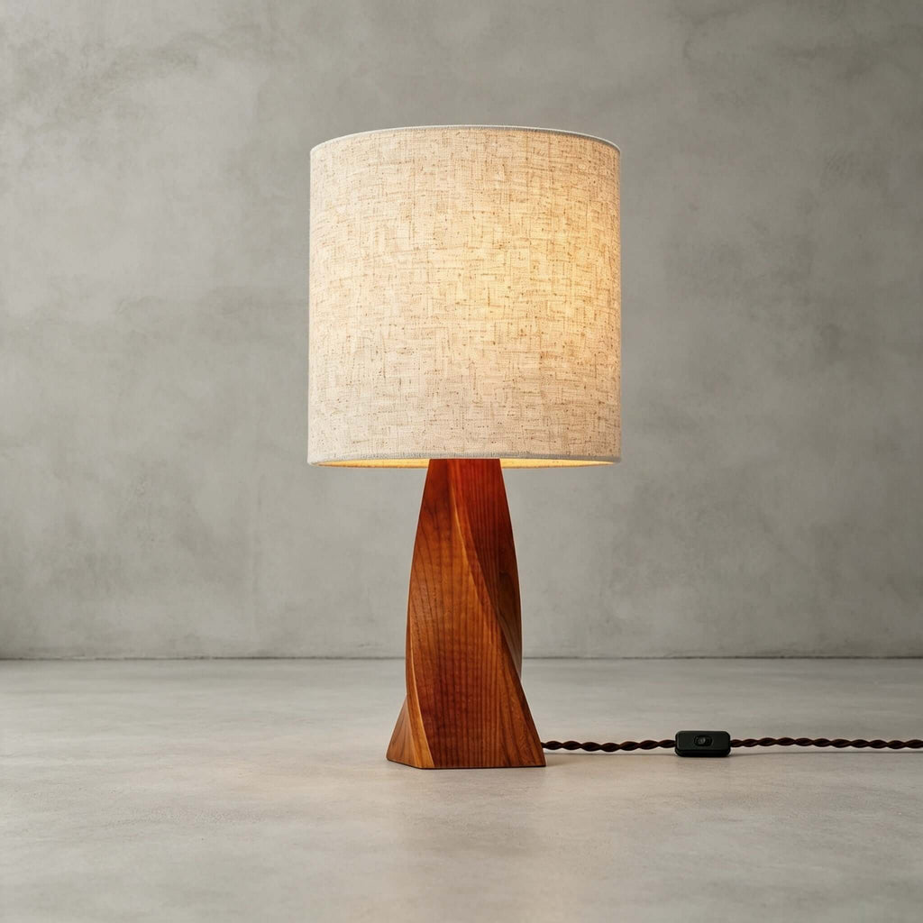 This Clérachic table lamp stands unlit on a pale concrete floor against a grey wall, with its braided black cord and switch trailing to one side.
