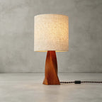 This Clérachic table lamp stands unlit on a pale concrete floor against a grey wall, with its braided black cord and switch trailing to one side.
