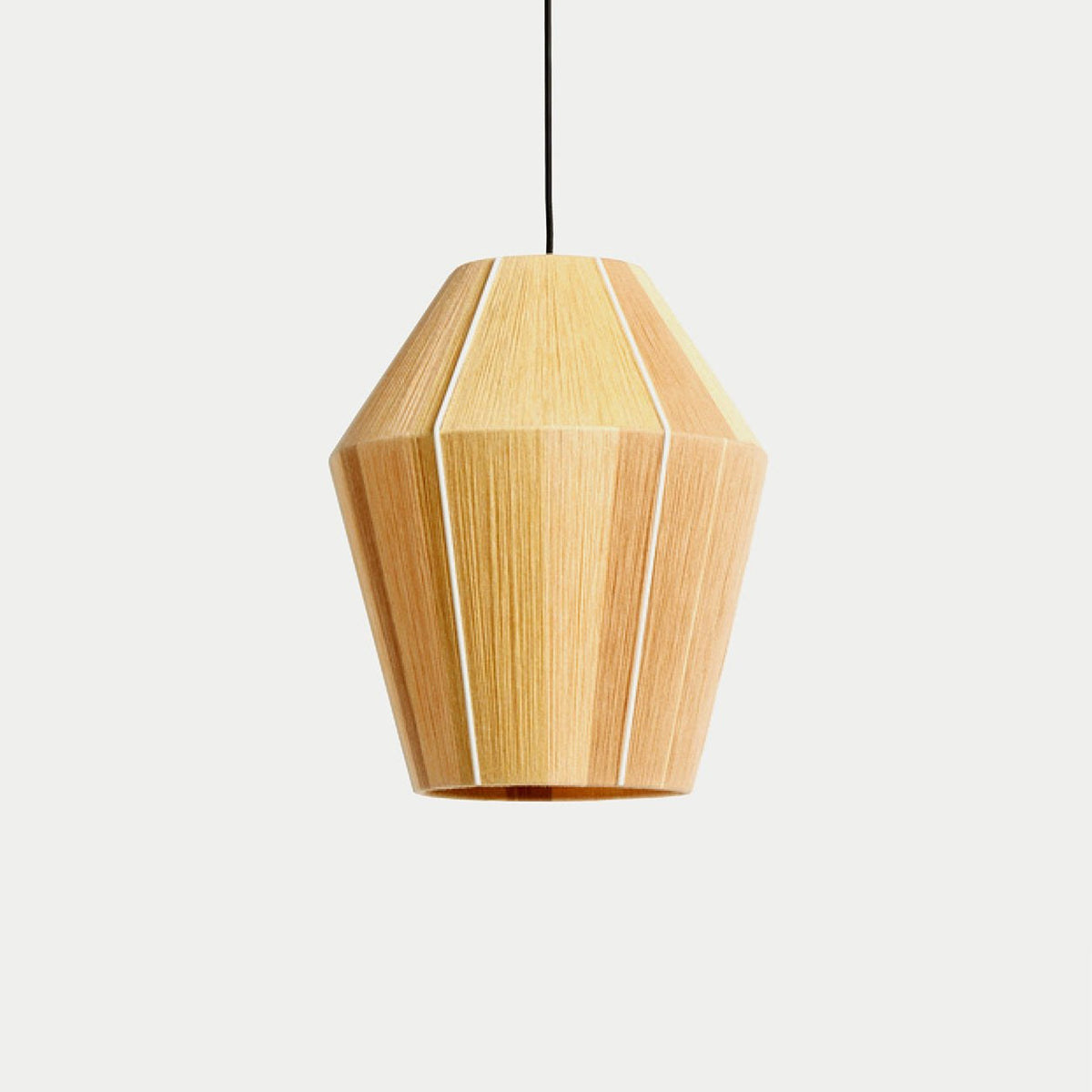 Clérachic hand-wound cotton lantern pendant in warm honey, a fine cream line down two of its seams, hanging from a black cord against a plain studio wall.