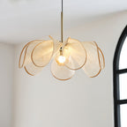 Glowing bloom-shaped shade of this Clérachic pendant against a white wall beside an arched black window.