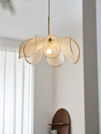 Lit bloom shade with a gold-toned stem hung near a sheer-curtained window, a Clérachic pendant seen from below.