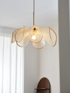 Warm bulb glowing through the beige woven petals of this Clérachic pendant, with white curtains in the background.