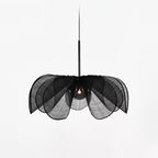 Black woven version of this Clérachic pendant on a light grey backdrop, its layered petals fanning around a dark bulb.