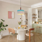 This Clérachic pendant in blue and white hangs in a bright dining nook with a white pedestal table and a pale green kitchen beyond.