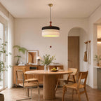 Black and white woven drum shade on this Clérachic pendant, hanging above a round wooden dining table in an arched room.
