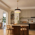 Above a kitchen island with two cane-backed stools, this Clérachic pendant shows a black and white woven drum shade.