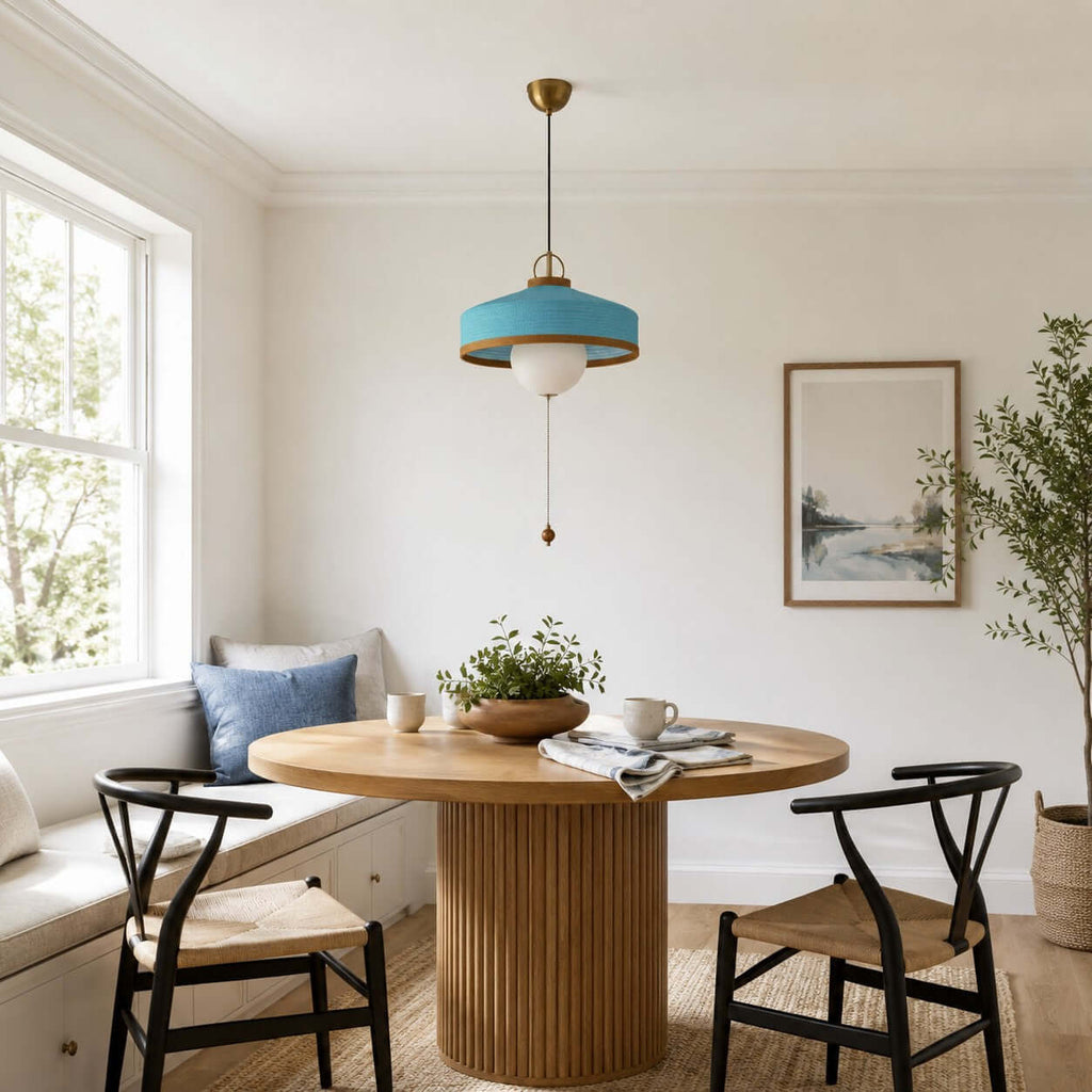 This Clérachic pendant in blue hangs in a breakfast corner with a window seat, a round table and two black chairs.