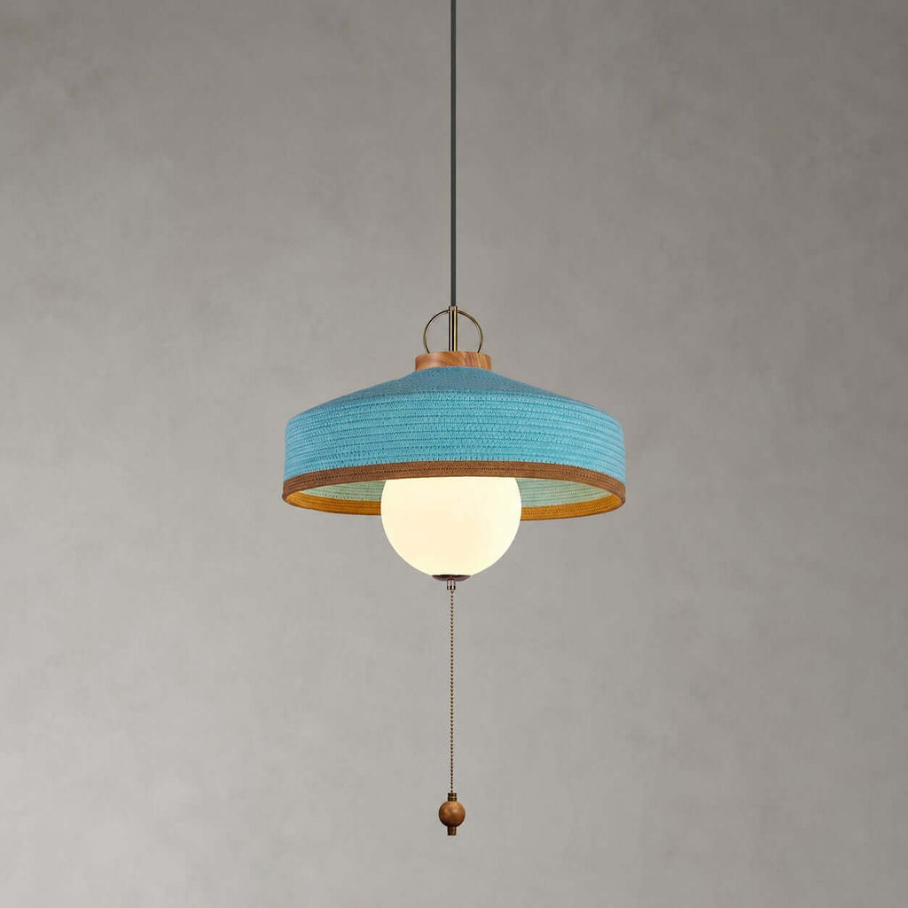Blue woven shade with a copper-toned inner rim, white glass globe and wooden pull bead on this Clérachic pendant, on grey.