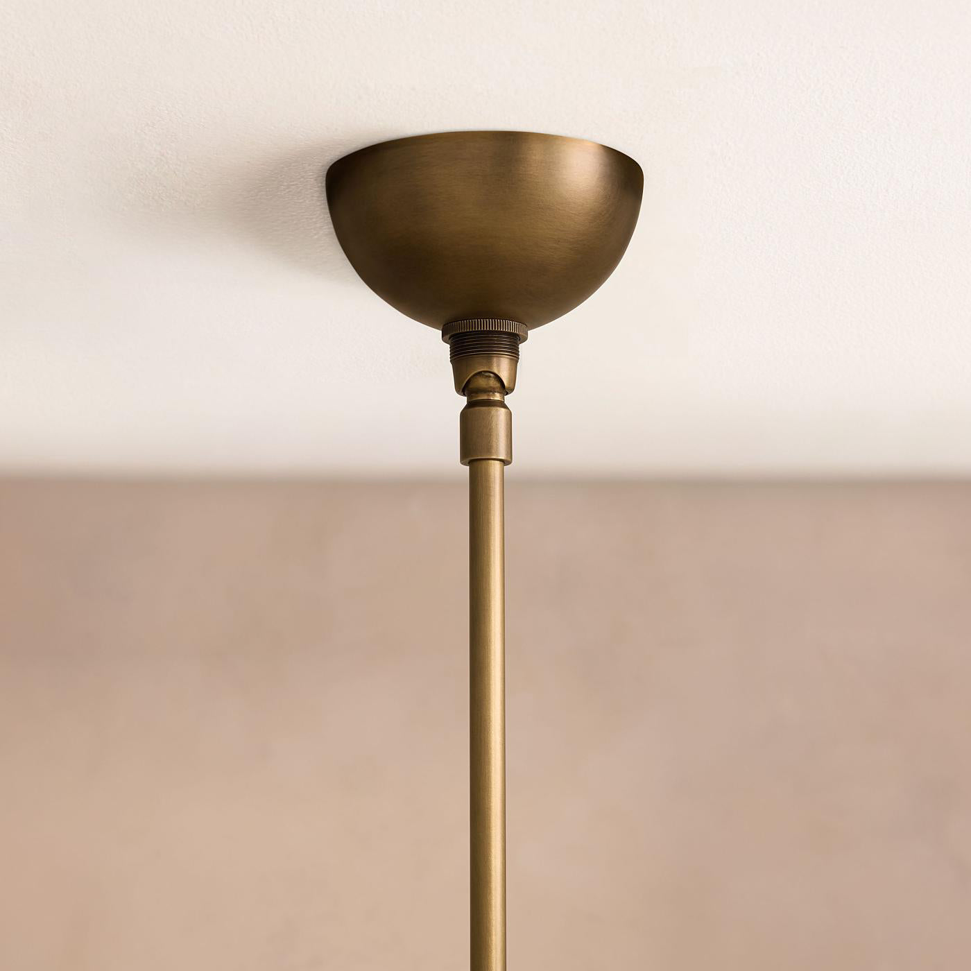 Clérachic Xenon ceiling canopy detail — a domed brushed brass mount with the slim brass drop rod running below it.