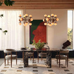 The Clérachic Xenon chandelier hung in a pair above a dark marble dining table in a beamed, curtained room.