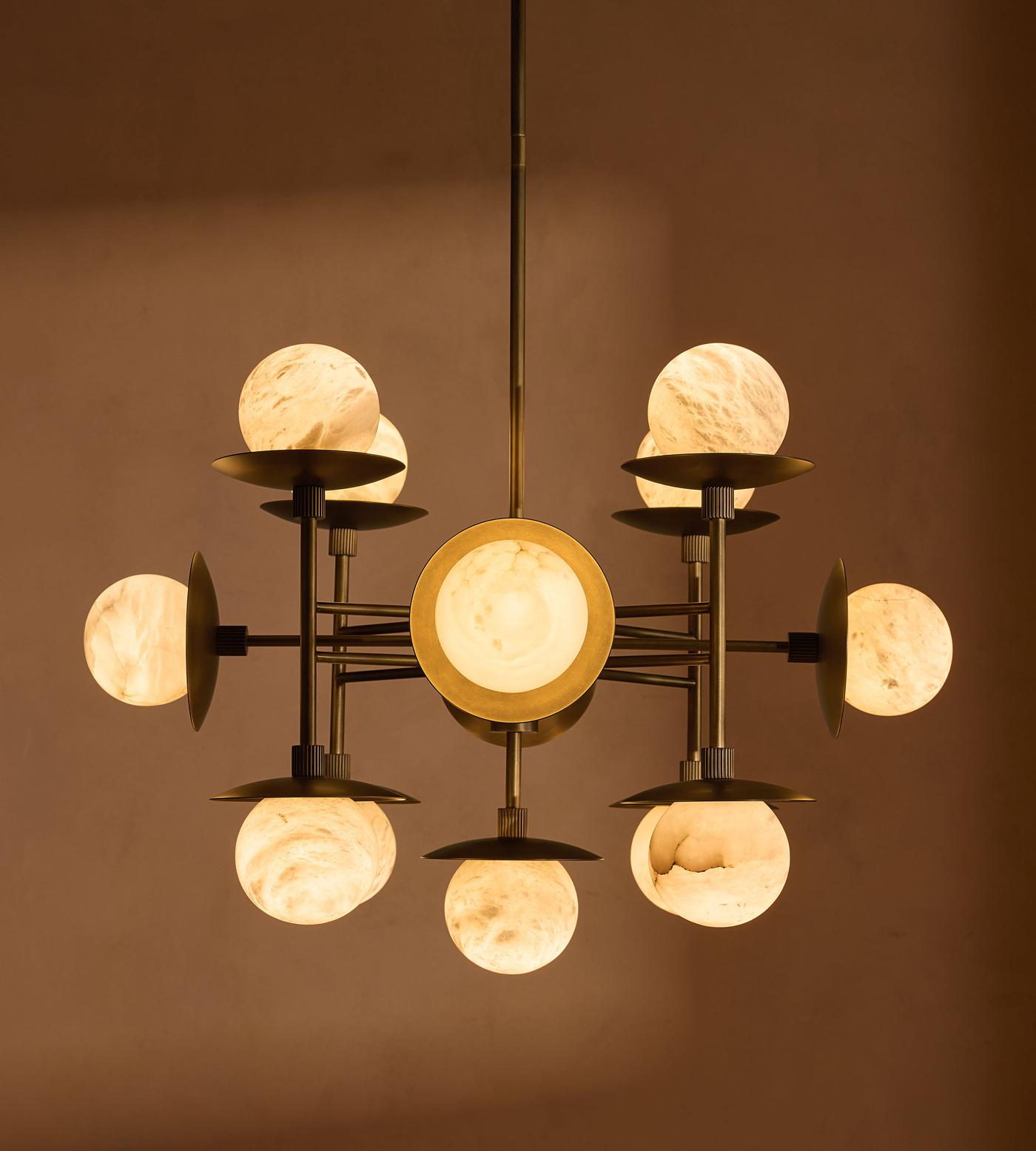 Clérachic Xenon chandelier switched on in a dim room, each alabaster sphere throwing a soft honey-toned light.