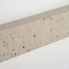Close view of the pitted, speckled surface of the travertine body of this Clérachic wall light.