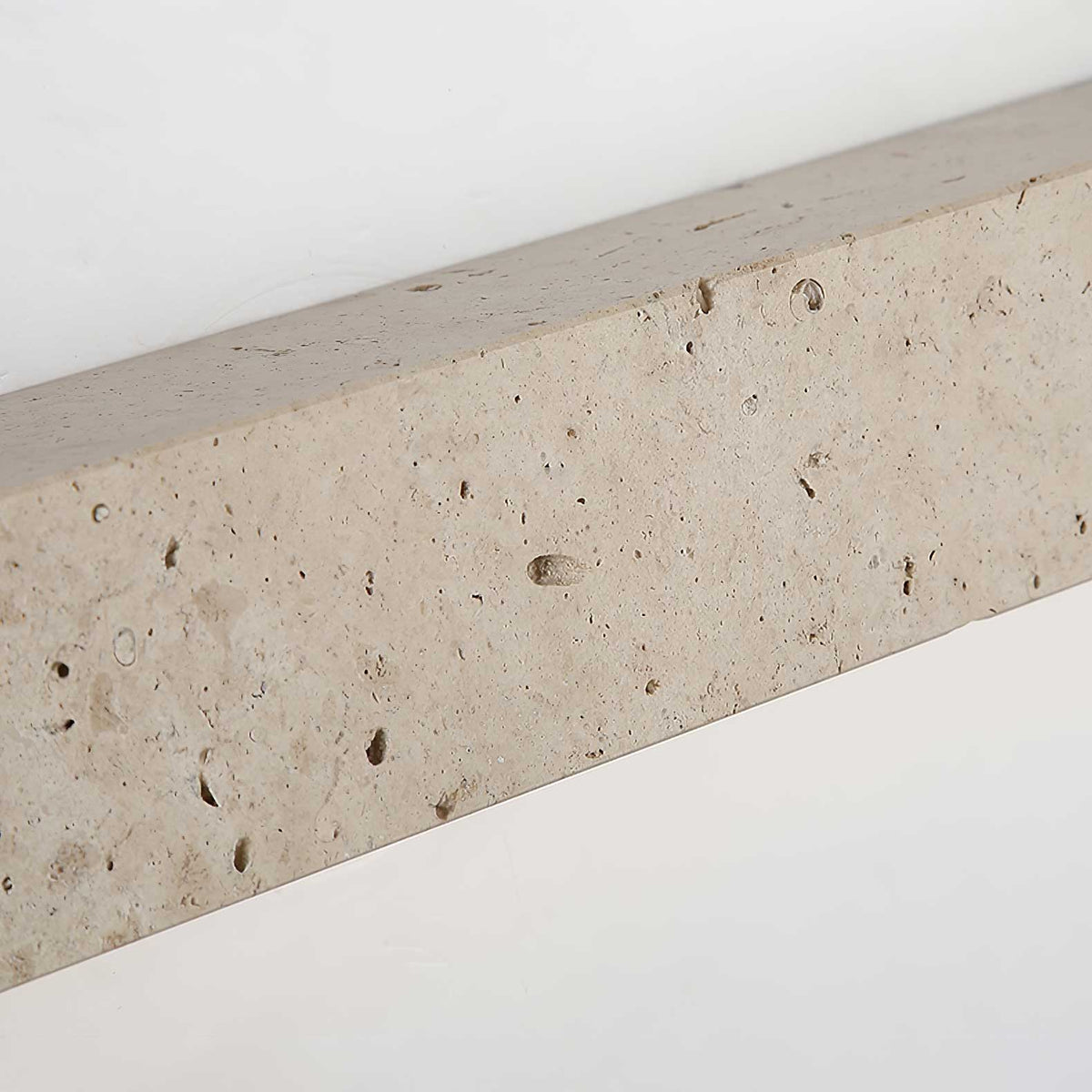 Close view of the pitted, speckled surface of the travertine body of this Clérachic wall light.