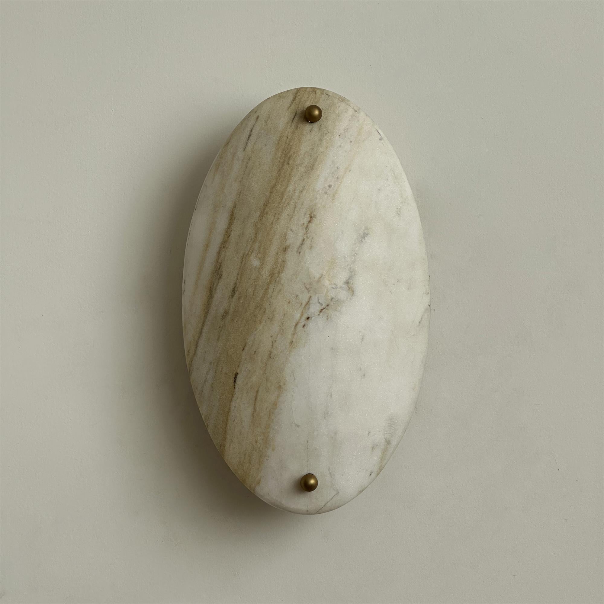 The Clérachic wall lamp seen close and unlit, tan and grey banding running the length of the natural stone oval.