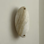 The Clérachic sconce unlit at a three-quarter angle, the stone oval standing proud of the wall on its brass mount.