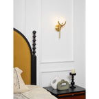The Clérachic sconce mounted above a black spindle headboard, casting warm light across the white wall panelling.