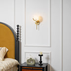 Clérachic wall light glowing on the panelled wall beside a mustard headboard and a black bedside table.