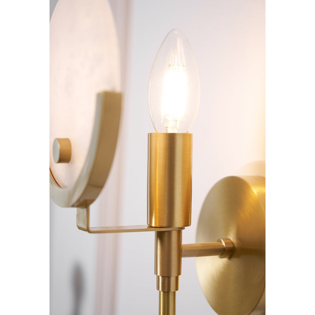 Macro of the Clérachic sconce's brushed brass socket cup and clear candle bulb, with the alabaster shade behind.