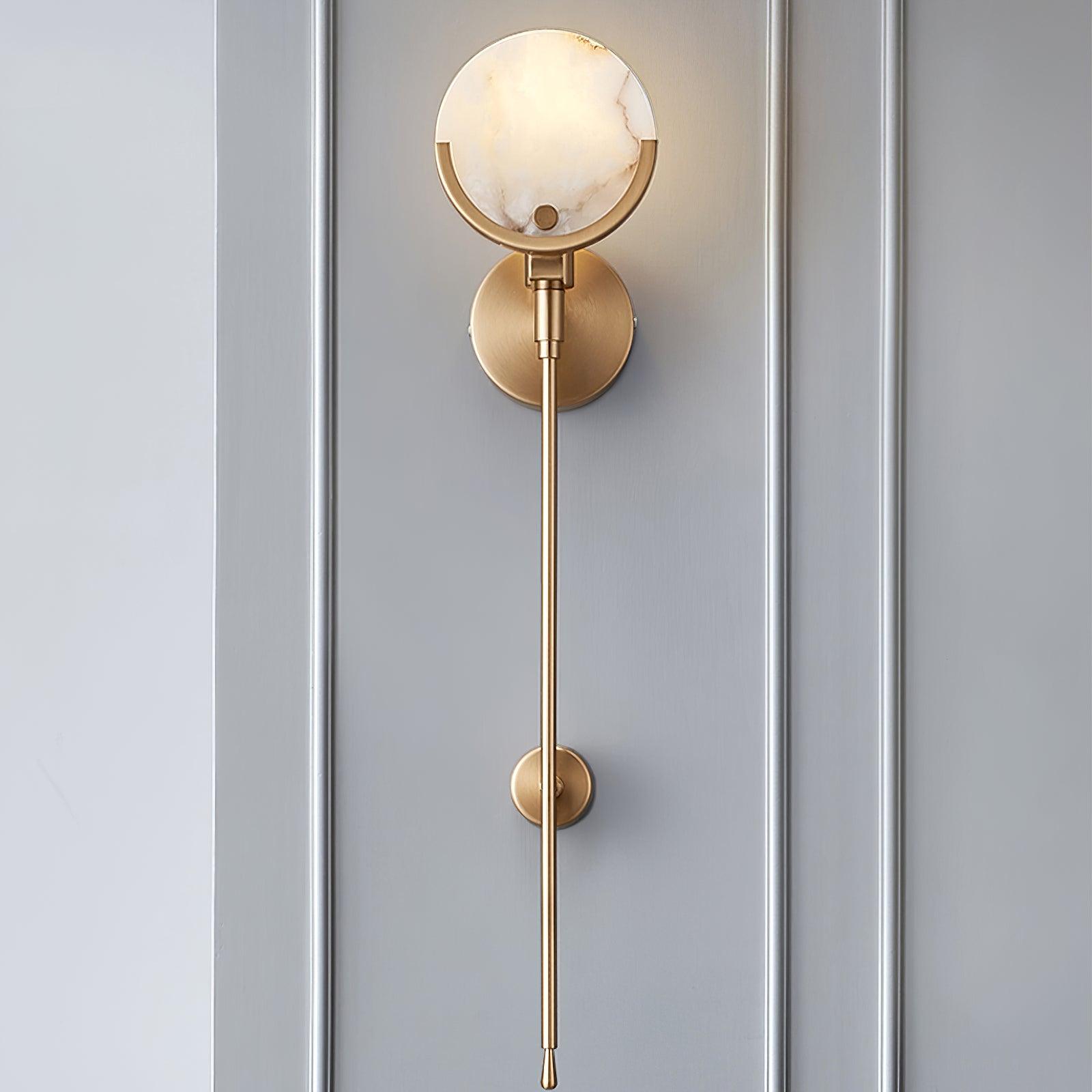 Clérachic sconce against grey panelling, the veined alabaster shade above a slim brass stem and low tie-back.