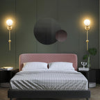 Clérachic wall lights lit in pairs on a deep green panelled wall behind a pink velvet bed.