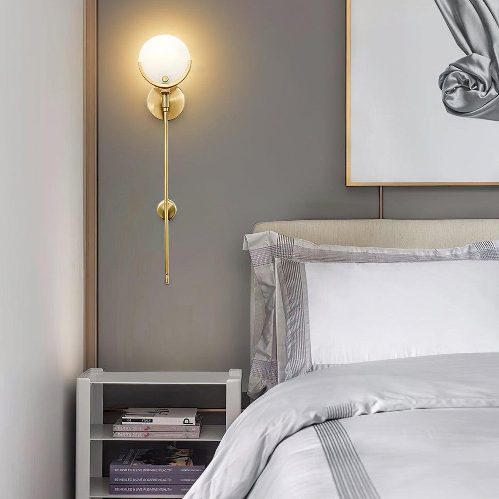 Clérachic wall light lit above a bedside shelf of books, in a soft grey bedroom with layered white linen.