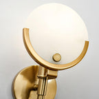 Close-up of the Clérachic shade seated in its brushed brass crescent, with the knurled fixing knob and backplate.