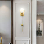 The Clérachic sconce lit on a panelled wall, seen through a doorway into a room hung with framed art.