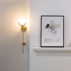 Clérachic wall light glowing beside a mantel where a framed print leans against the wall.