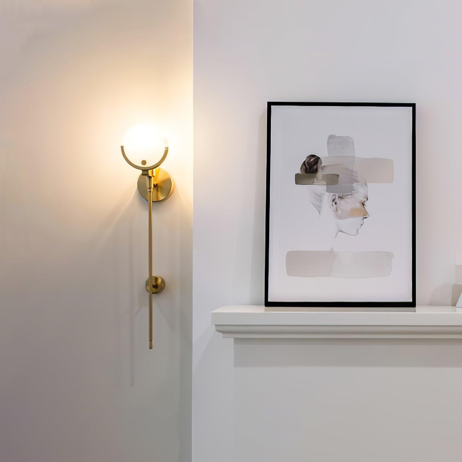 Clérachic wall light glowing beside a mantel where a framed print leans against the wall.