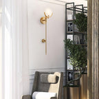 The Clérachic wall light beside a sheer-curtained window, with an armchair and black shelving behind.