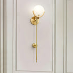 The Clérachic wall light against pale sage panelling, globe shade and brass stem in one clean vertical.