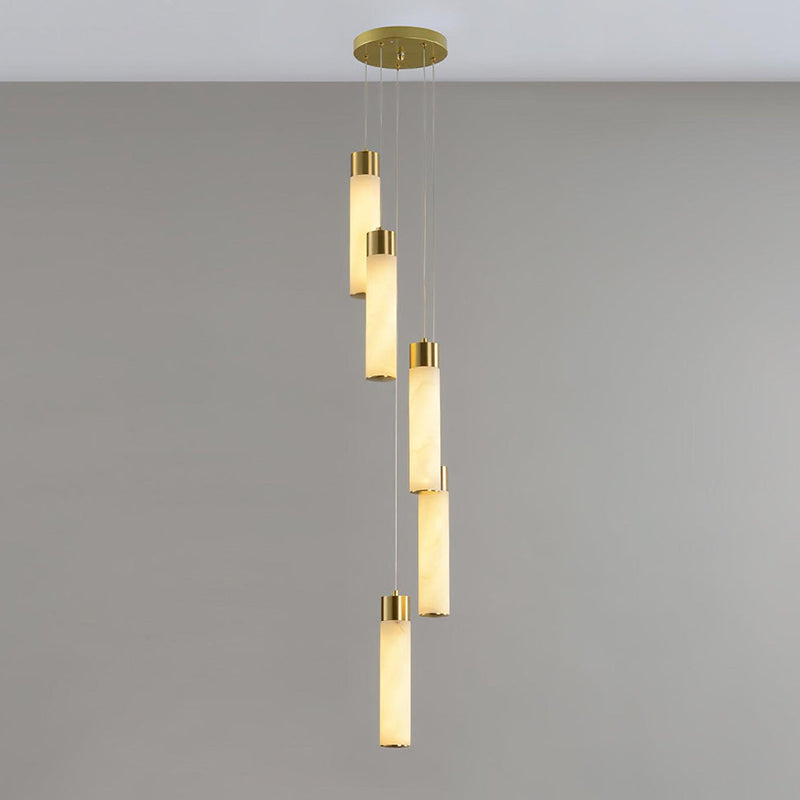 Clérachic Zeal cascade chandelier with five alabaster drops spiralling from a round brushed brass canopy on a bare grey wall.