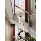 Clérachic Zeal chandelier hung beside a stone-clad staircase, warm light washing the treads and the panelled hall.