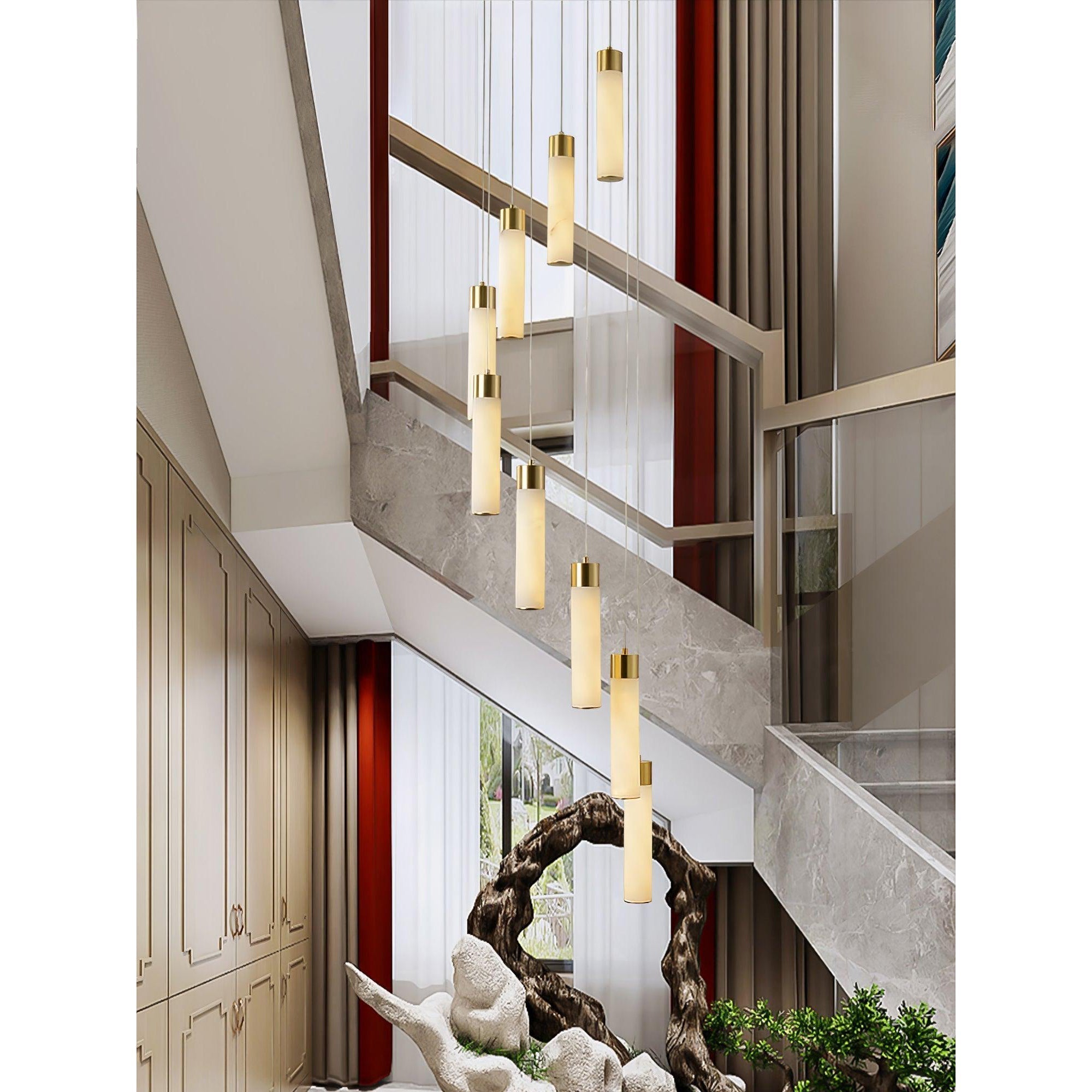 Clérachic Zeal chandelier hung beside a stone-clad staircase, warm light washing the treads and the panelled hall.