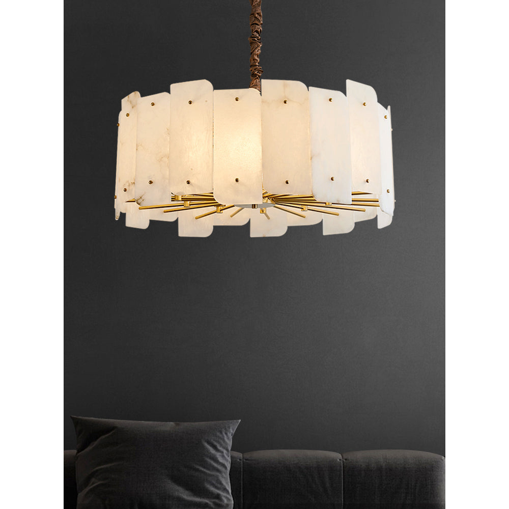 The Clérachic Zoe alabaster chandelier glowing warm against a charcoal wall above a dark velvet sofa in a living room.