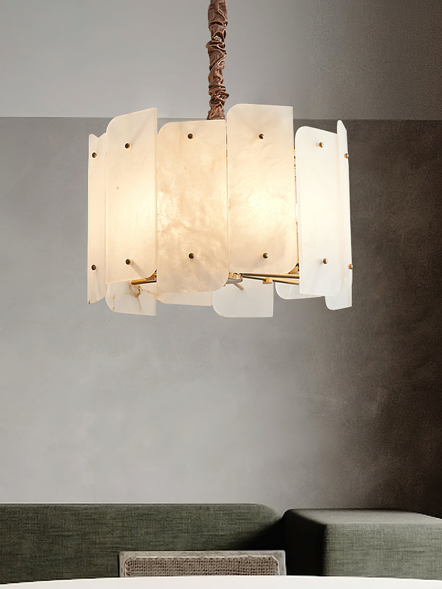 Close view of the Clérachic Zoe chandelier lit over a sitting area, the alabaster turning honey-warm around the twisted stem.