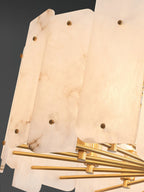 Macro detail of the Clérachic Zoe chandelier, warm light revealing the amber veining inside each alabaster panel and its brass stud.