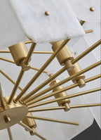 Underside of the Clérachic Zoe chandelier showing the brushed brass hub, radiating rods and candelabra sockets between the panels.