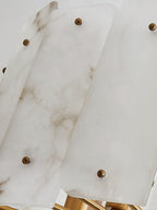 Overlapping alabaster panels on the Clérachic Zoe chandelier, each pinned with a round brass stud, veining running through the stone.