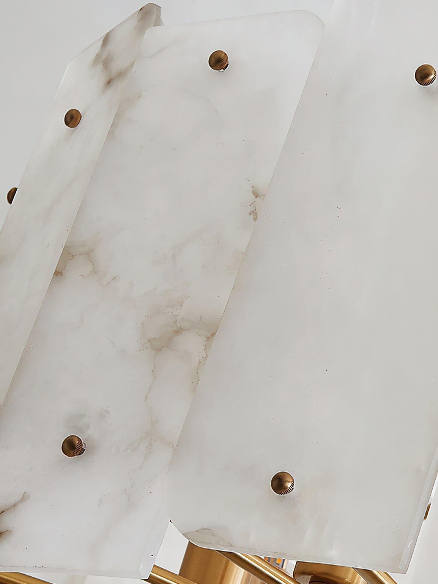 Overlapping alabaster panels on the Clérachic Zoe chandelier, each pinned with a round brass stud, veining running through the stone.