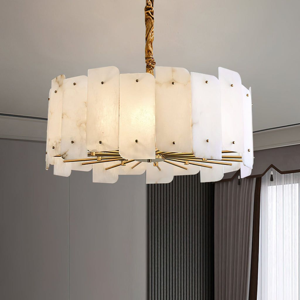 The Clérachic Zoe alabaster chandelier lit in a grey panelled room, hanging low from its brass stem beside floor-length curtains.
