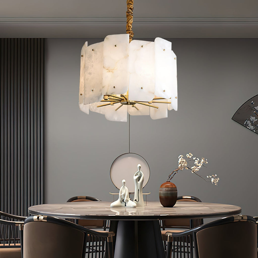 Clérachic Zoe chandelier spreading warm light across a round dining table set with pale sculptures and a small vase.