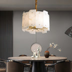 Clérachic Zoe chandelier spreading warm light across a round dining table set with pale sculptures and a small vase.