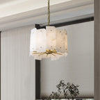 Clérachic Zoe alabaster chandelier on a brass chain beside a window dressed in woven grey blinds, olive branches below.