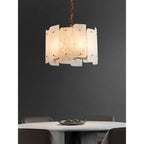 The five-light Clérachic Zoe chandelier lit over a round marble dining table, its stone panels glowing against a charcoal wall.