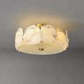 Clérachic ceiling light at a shallow angle, brass studs pinning each alabaster slab to the low drum frame.